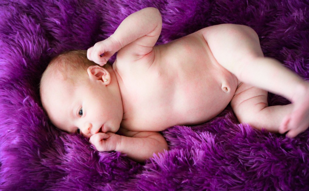 младенец лежит на фиолетовом пледе