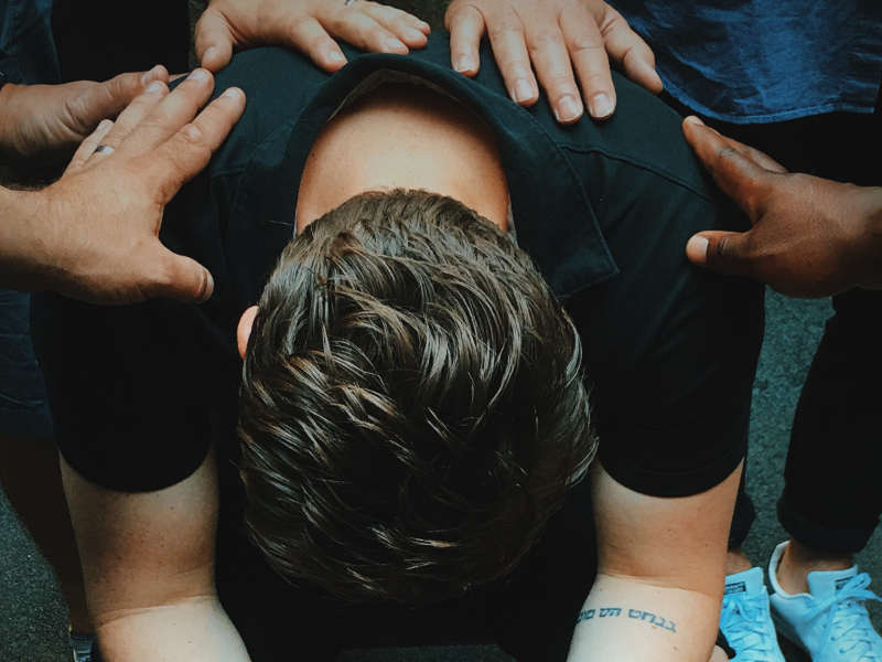 man sitting on chair holding and surrounded by people