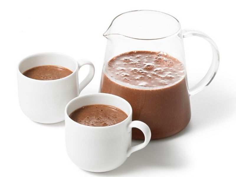 Ароматный свежий какао в чайнике и двух чашках на столе