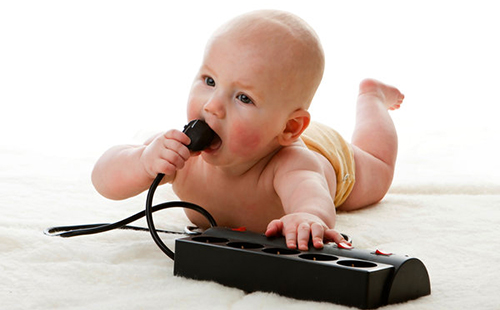 Ребёнок пытается сунуть в рот электрический штепсель, что абсолютно недопустимо